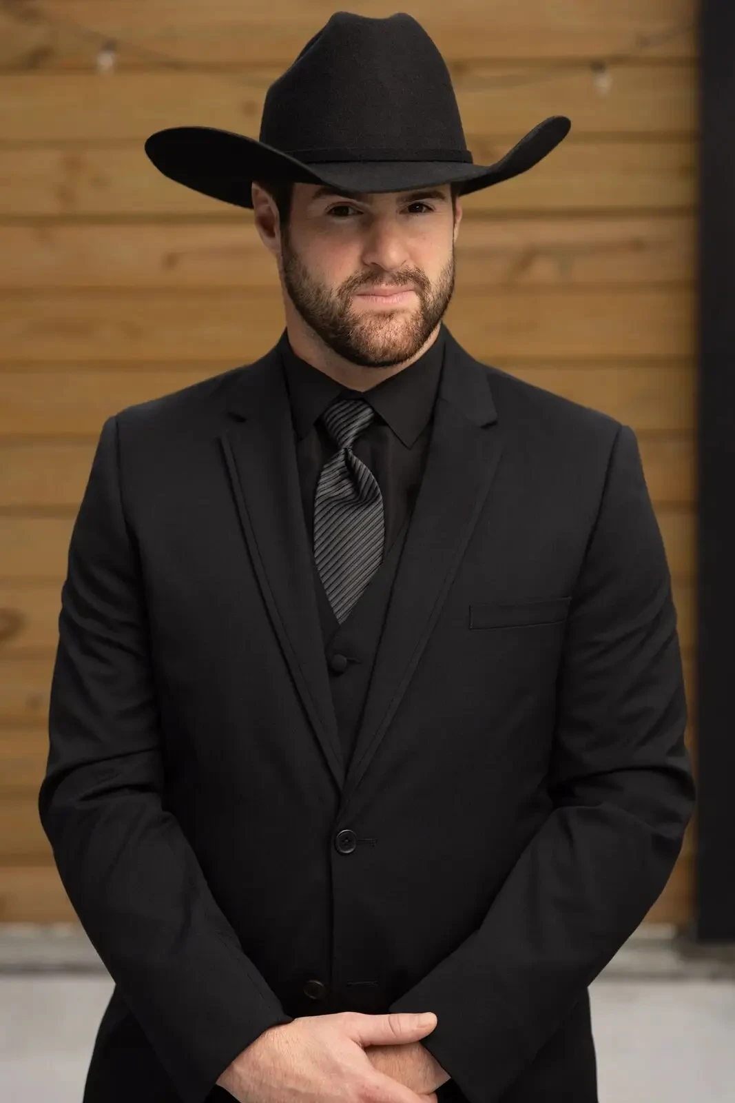 image shows a male model wearing a black suit