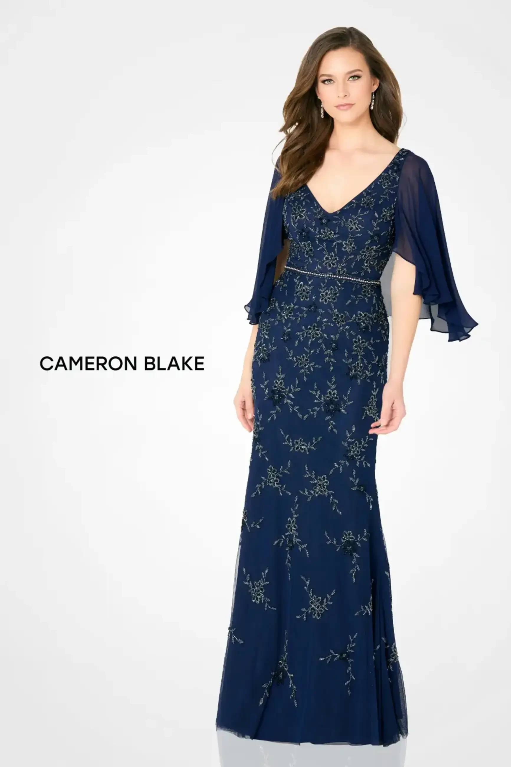 Model is wearing a fit and flare evening gown with a v-neckline and sequin tulle