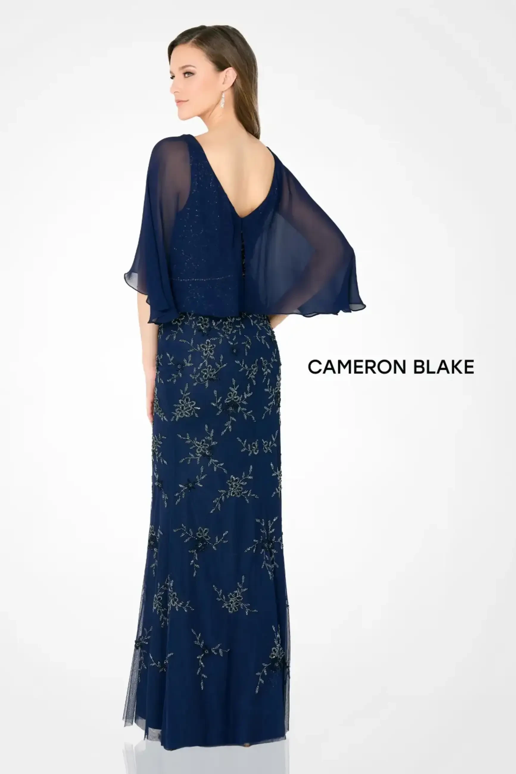 Model is wearing a fit and flare evening gown with a v-neckline and sequin tulle