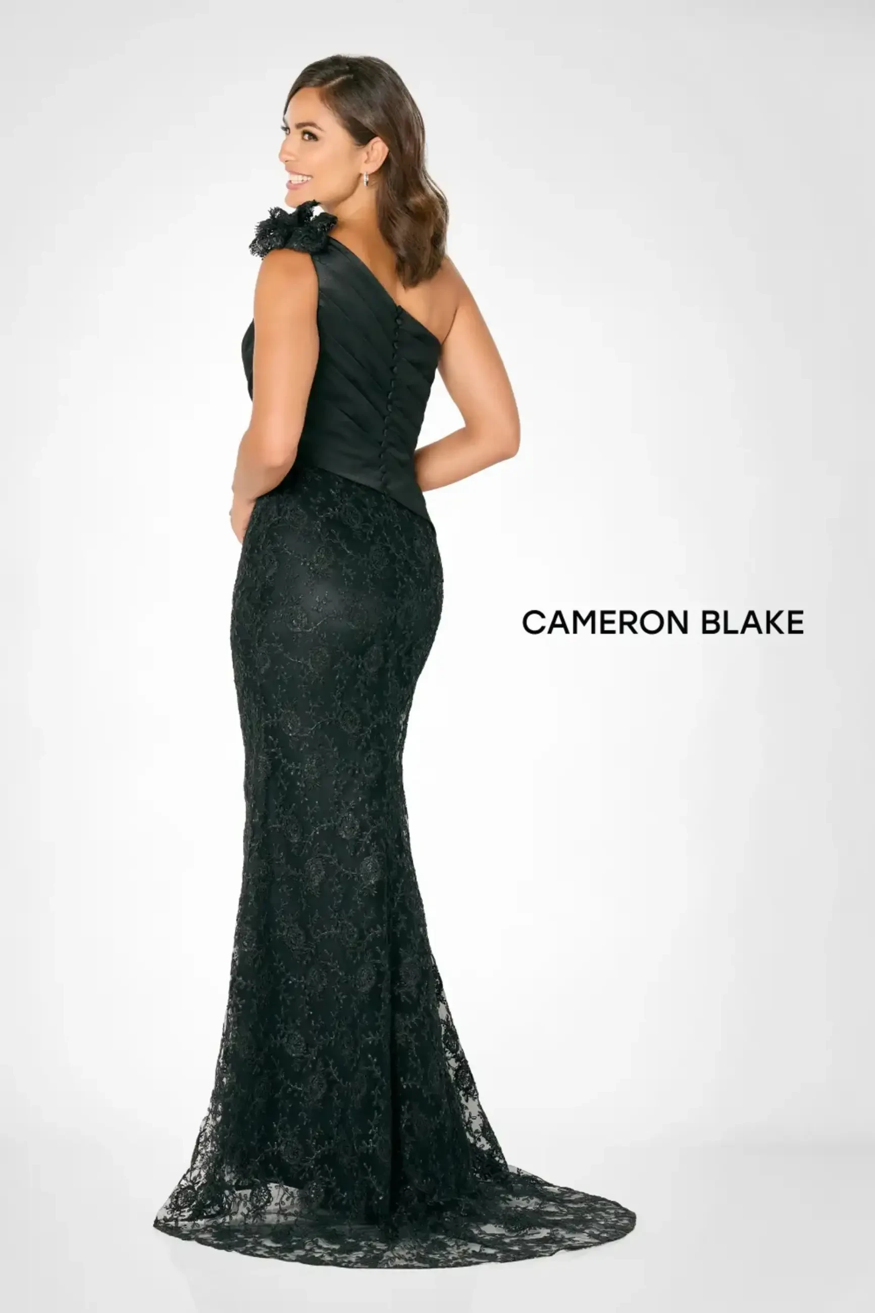 Model is wearing a fit and flare bridal gown with a one shoulder neckline and three dimensional lace detailing 