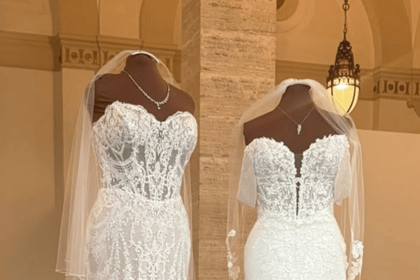 Two lace wedding dresses with sheer veils displayed on mannequins inside a bridal boutique