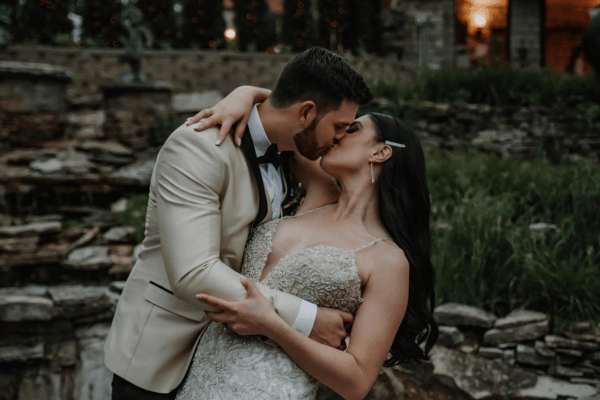 Bride and groom sharing a kiss with grass and rocks behind them