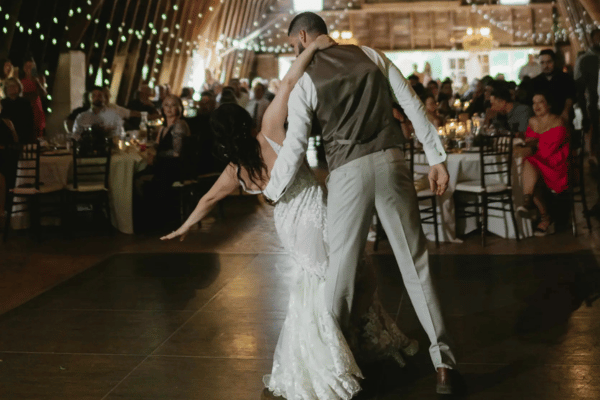 Back view of the bride and groom dancing at the reception, with tables, chairs, and guests in front of them at Blue Dress Barn