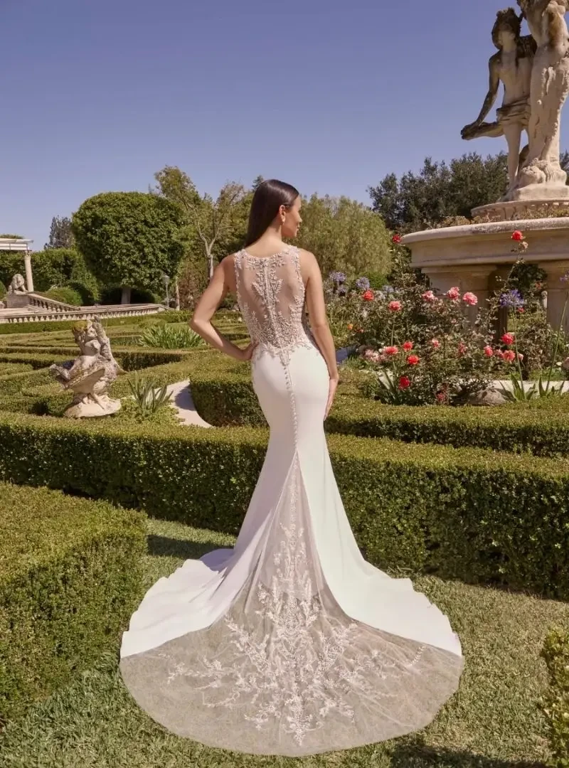 Back view of a fitted wedding dress with an illusion lace bodice, covered buttons, and a long lace-trimmed train.