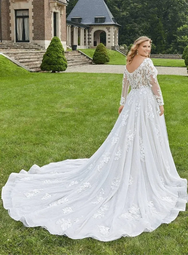 Bride wearing a long-sleeve lace A-line wedding dress with a sweeping chapel train, standing on the lawn of an elegant estate for Elegance Wedding.